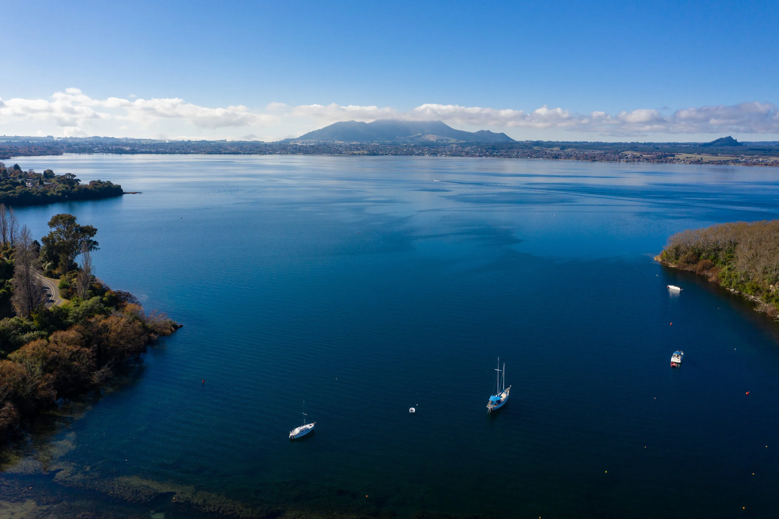 Boats anchored on Lake Taupō with town and hills in the distance